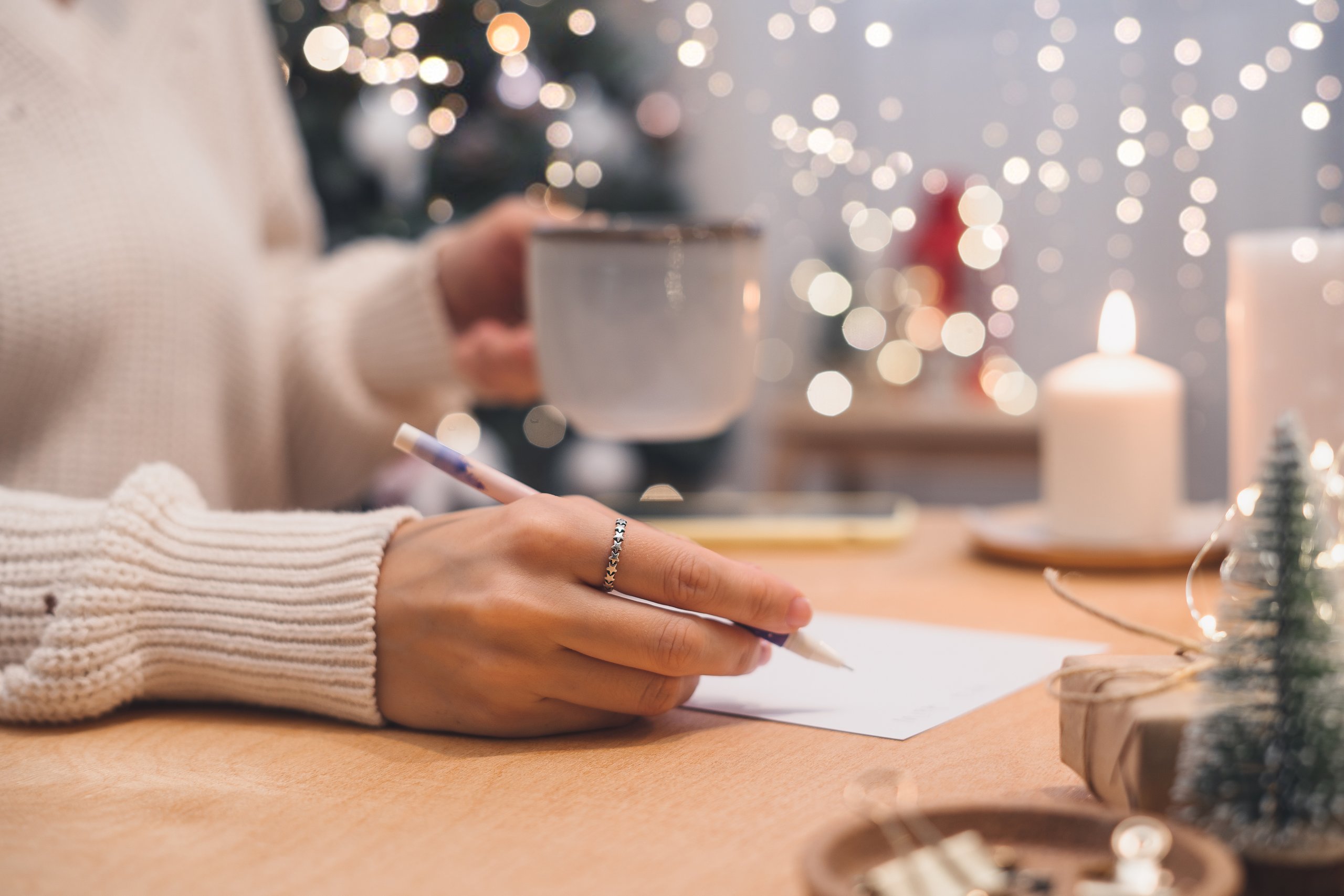 Hand schreibt mit einem Stift weihnachtliche Worte auf Papier